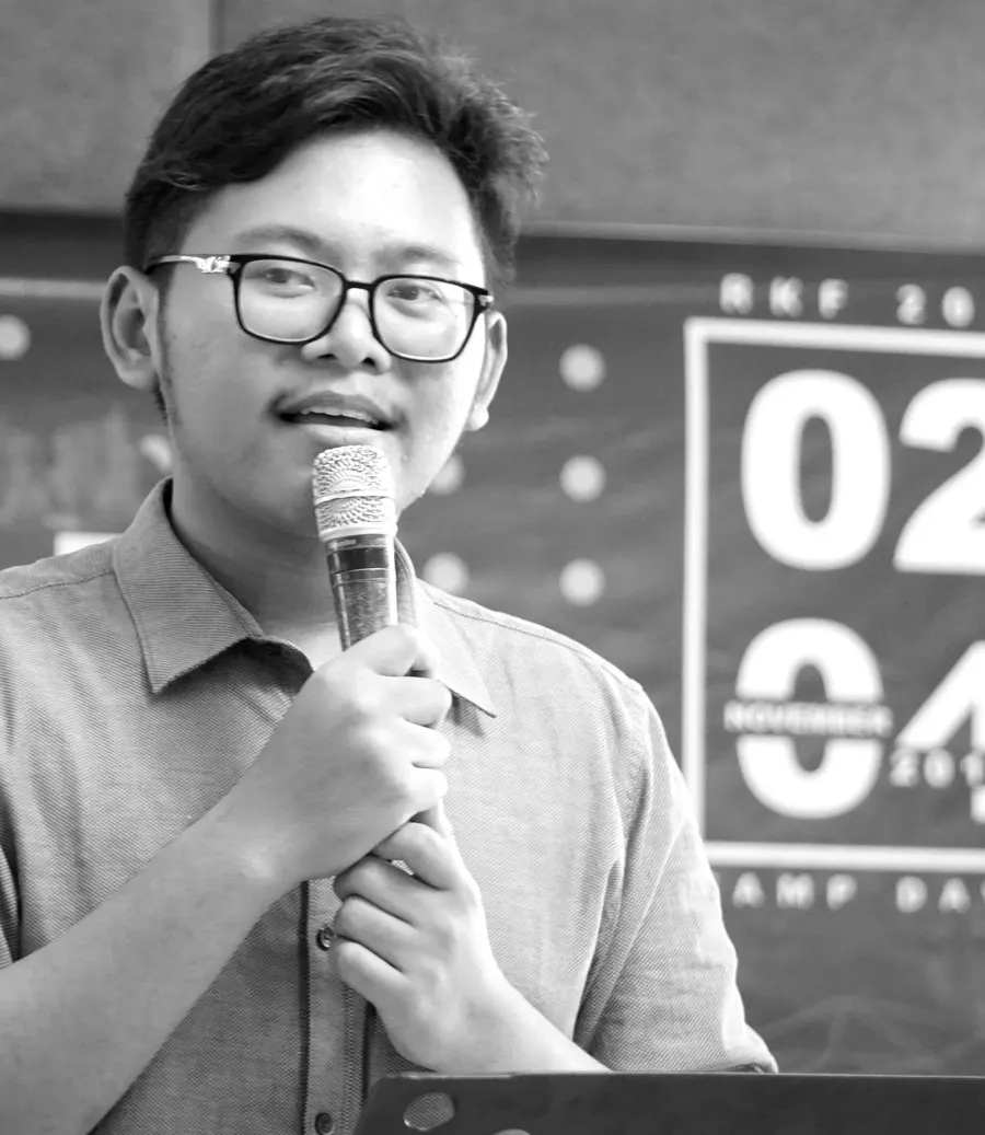 Samuel Manalu speaking into a microphone at an event